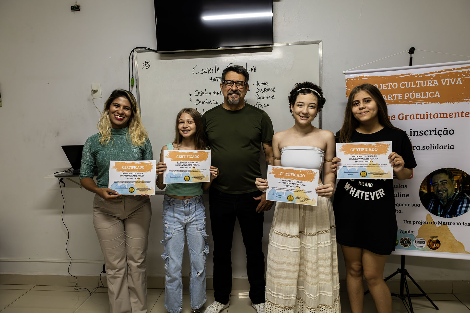 Pessoas segurando certificados em frente a quadro branco.