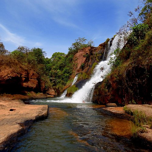 Cachoeira rodeada por vegetação exuberante.