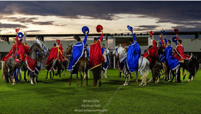 Grupo a cavalo com trajes coloridos em campo.