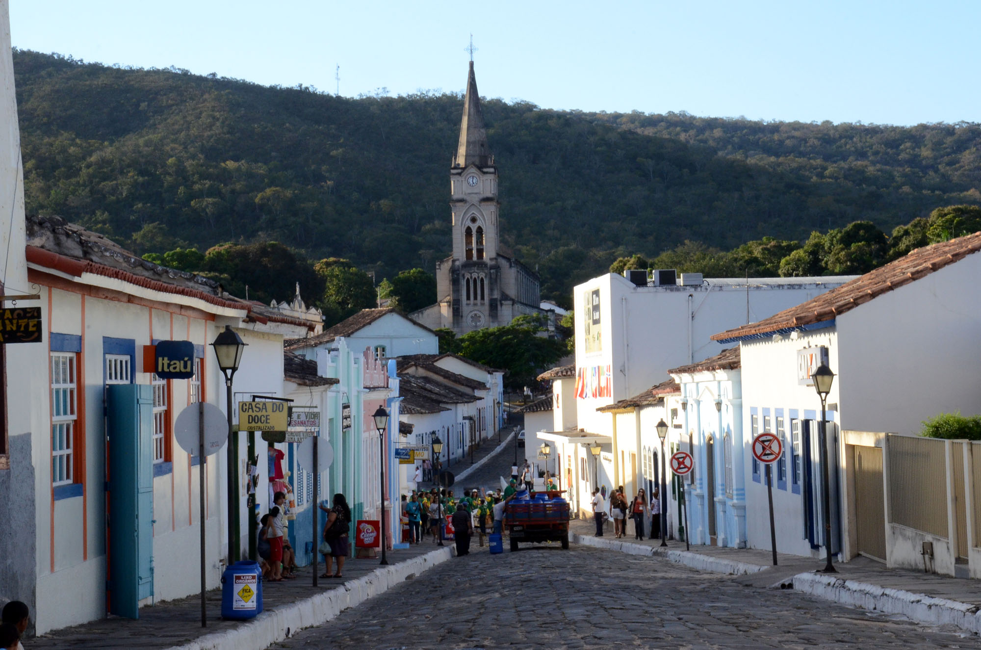Rua histórica com igreja ao fundo em paisagem montanhosa.