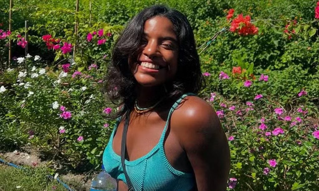 Mulher sorrindo em jardim florido.