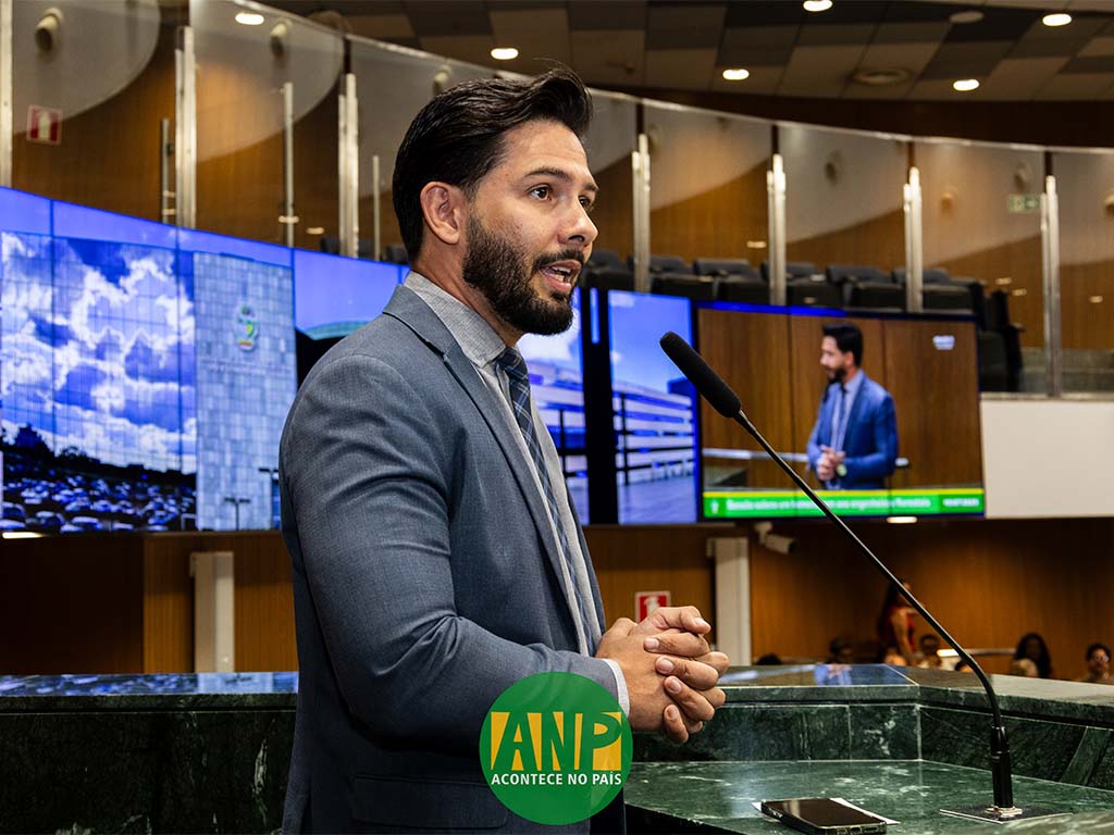 Homem discursando no auditório com telões ao fundo.