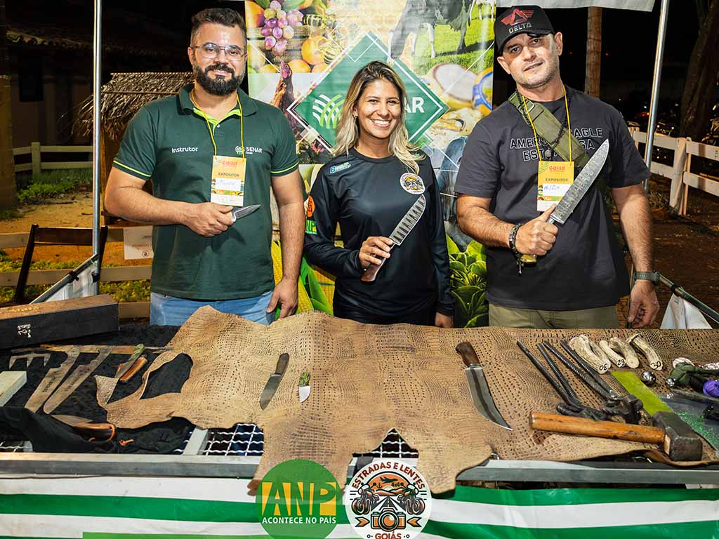 Pessoas exibindo facas artesanais em evento.
