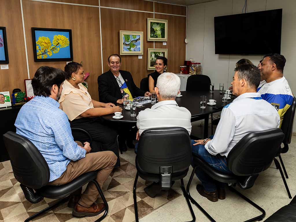 Pessoas em reunião em sala com quadros na parede.