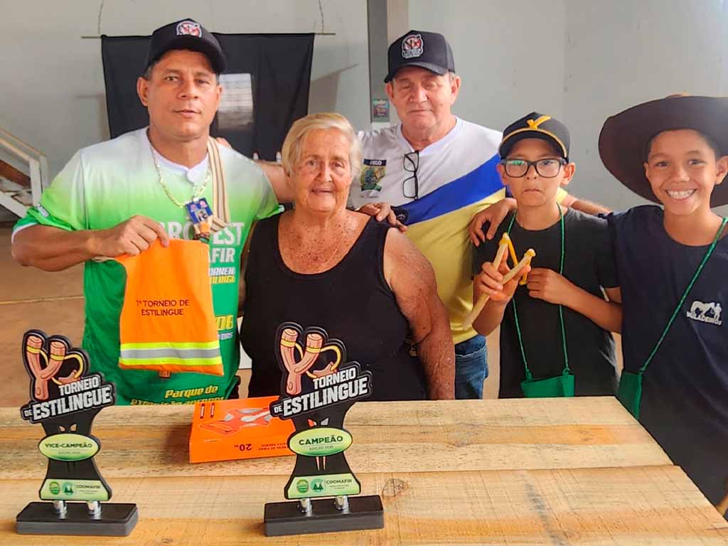 Pessoas posam com troféus de torneio de estilingue.