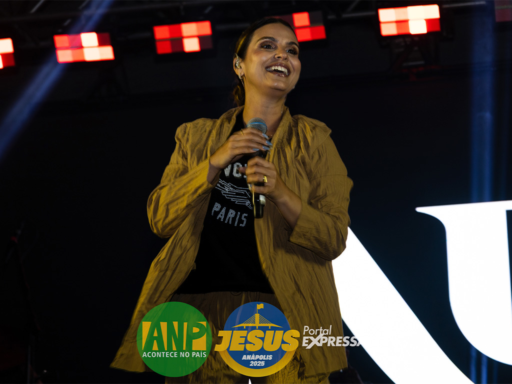 Cantora sorrindo em show, palco iluminado.