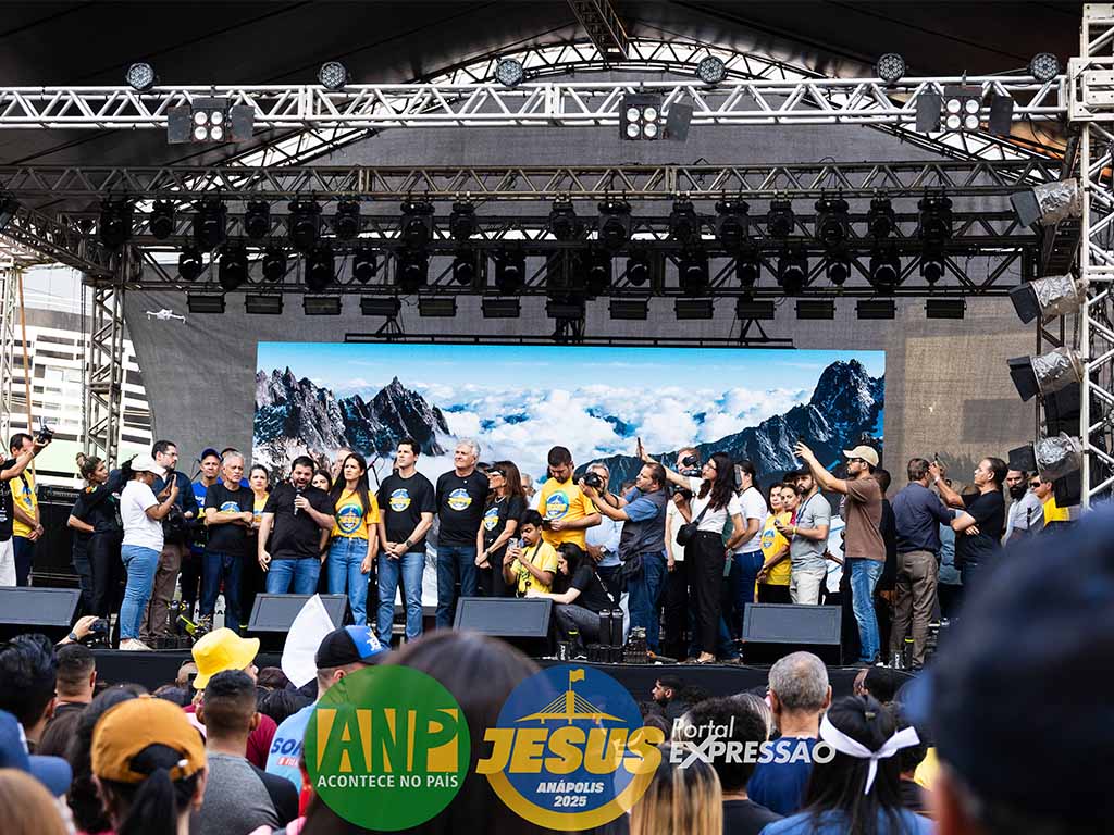 Evento com pessoas em palco e projeção de montanhas.