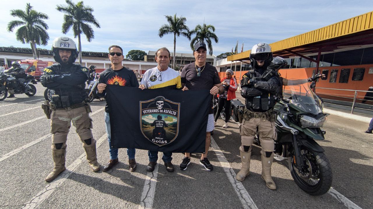 Motociclistas em evento com policiais e bandeira.