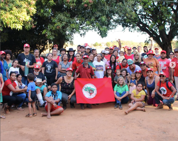 Grupo com bandeira vermelha em ambiente externo.