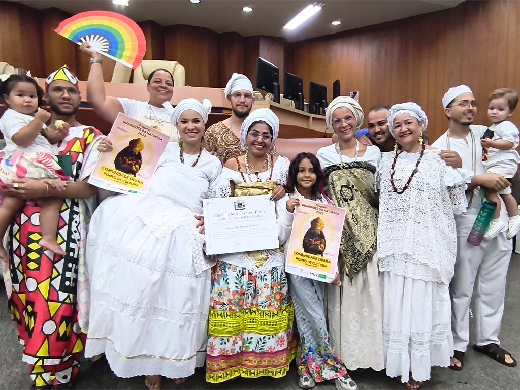 Grupo em trajes tradicionais celebra em cerimônia de premiação.