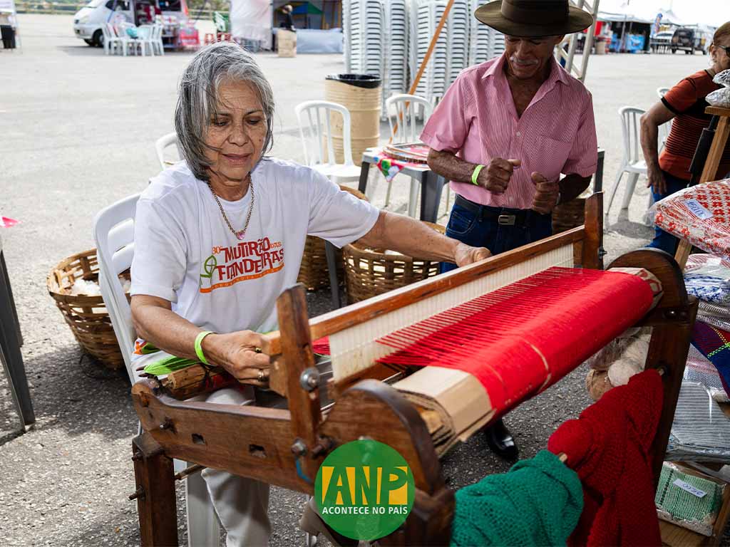 Artesã tecendo em tear tradicional, feira ao ar livre.