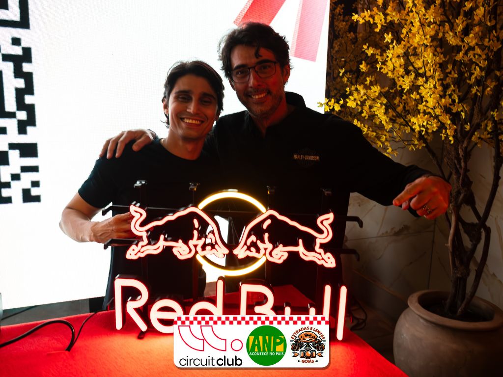 Dois homens sorrindo segurando logo da Red Bull.