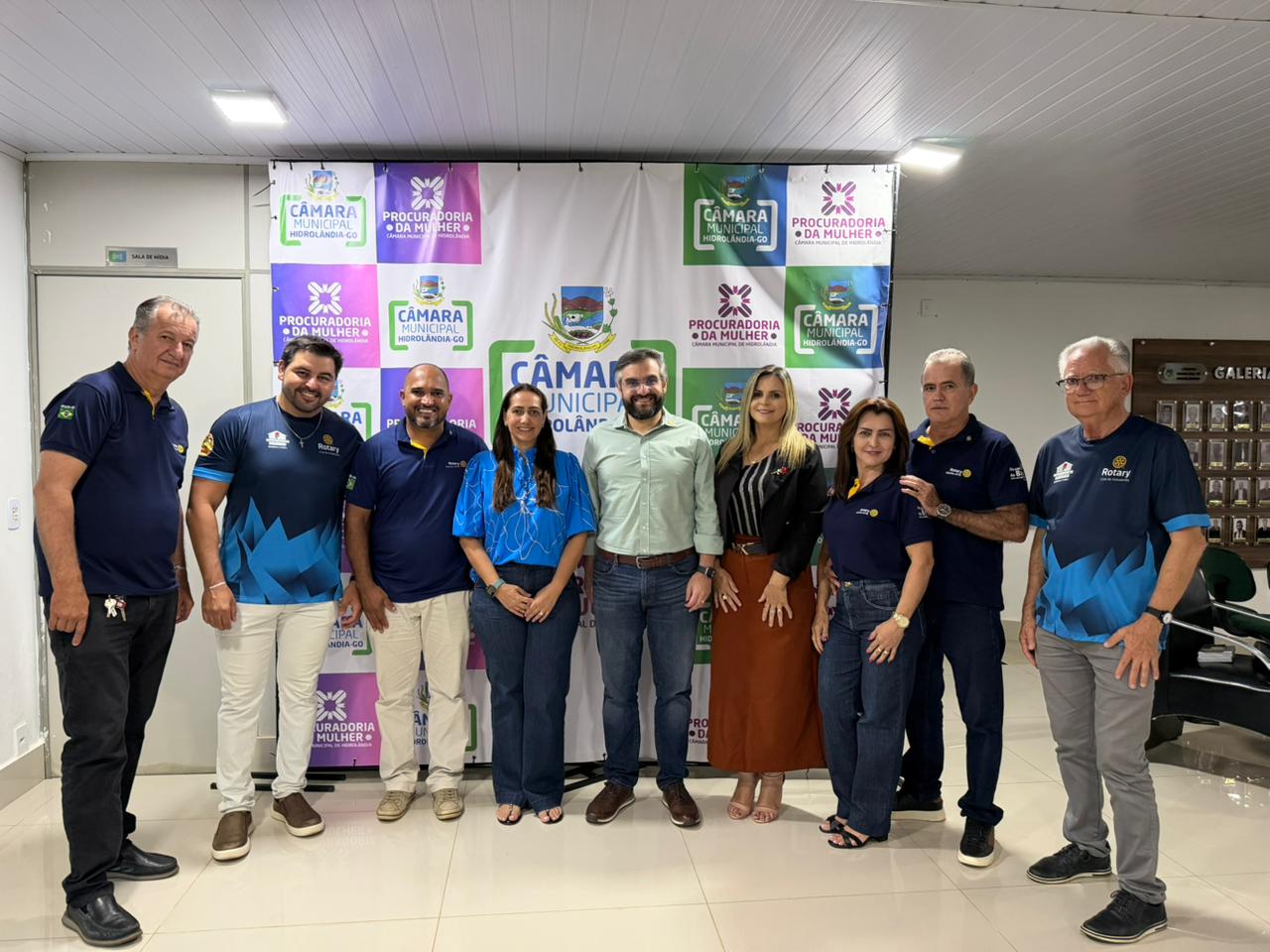 Pessoas posando em frente a banner da Câmara Municipal.