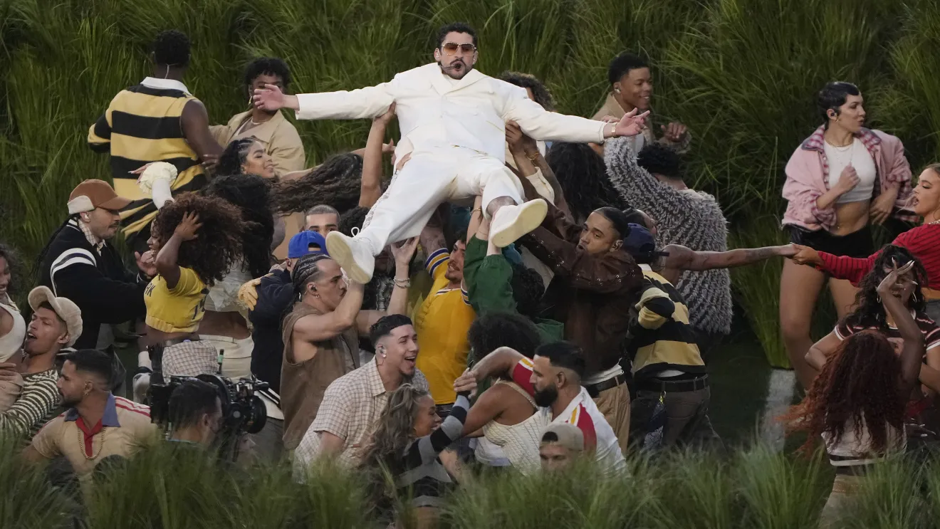 Pessoa em roupas brancas sendo levantada por multidão.