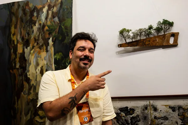 Homem aponta para obra de arte na parede