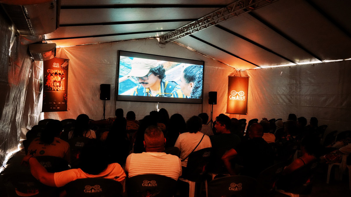 Público assistindo filme em telão dentro de tenda