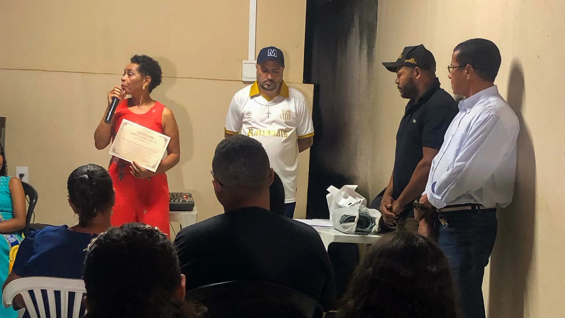 marlene divina de oliveira e sousa discursa segurando certificado em evento.