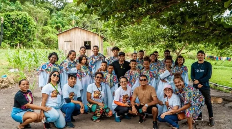 Grupo de pessoas sorrindo ao ar livre com árvores.