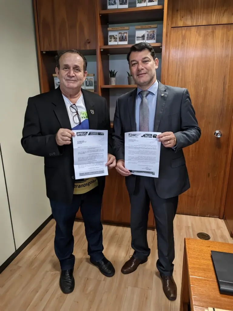 Dois homens segurando documentos em escritório de madeira.